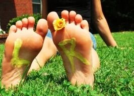 Piedi senza un fungo con un fiore tra le dita